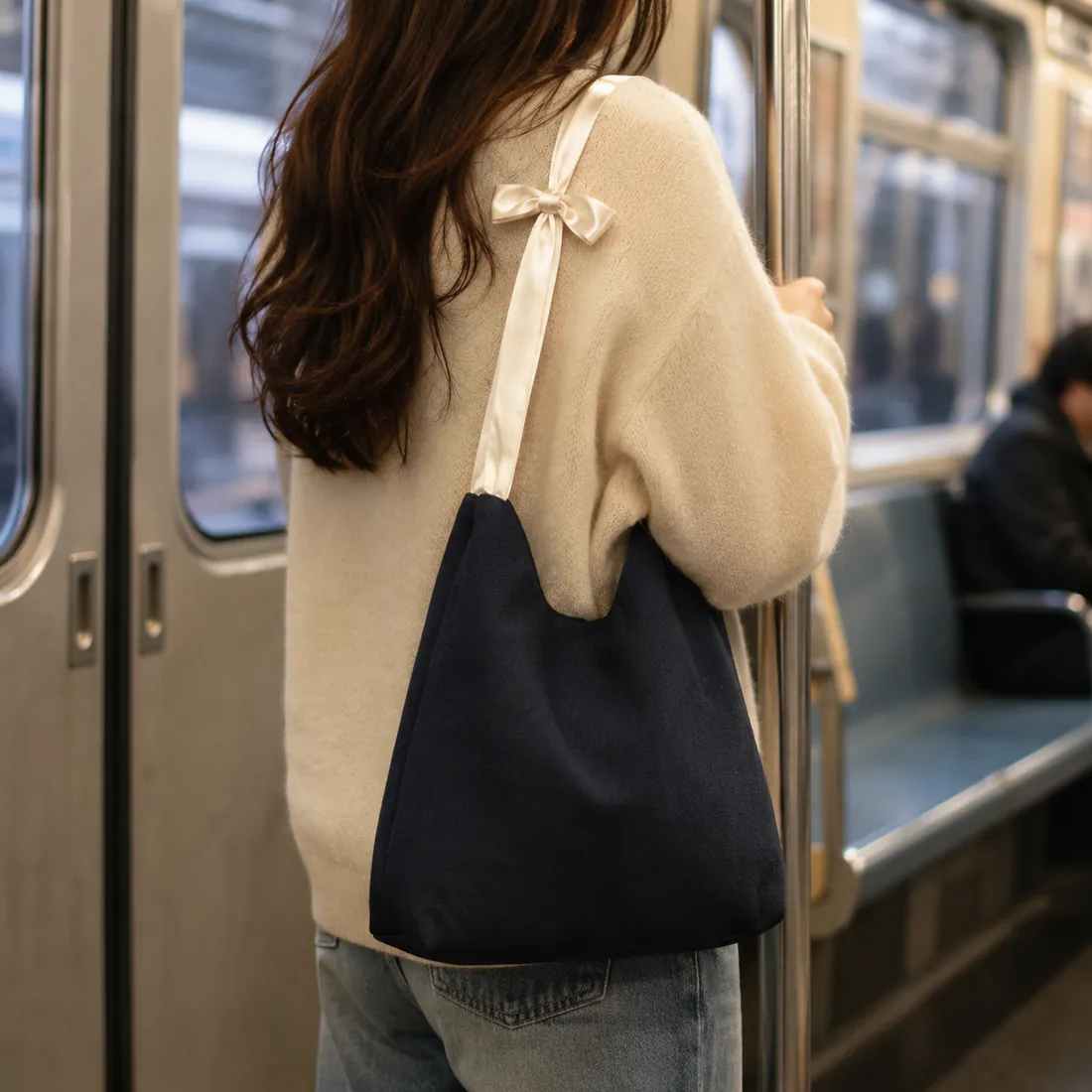 Black bow-handle canvas bag on a subway / 地铁场景中的黑色蝴蝶结手柄帆布包