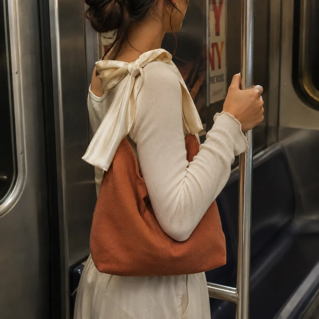 Rust bow-handle canvas bag on a subway / 地铁场景中的铁锈色蝴蝶结手柄帆布包