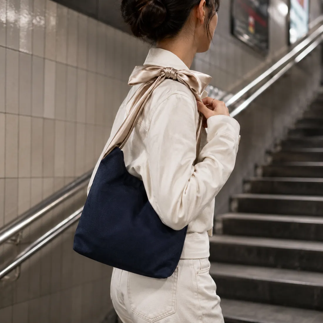 Navy bow-handle canvas bag on subway stairs / 地铁楼梯场景中的藏蓝色蝴蝶结手柄帆布包